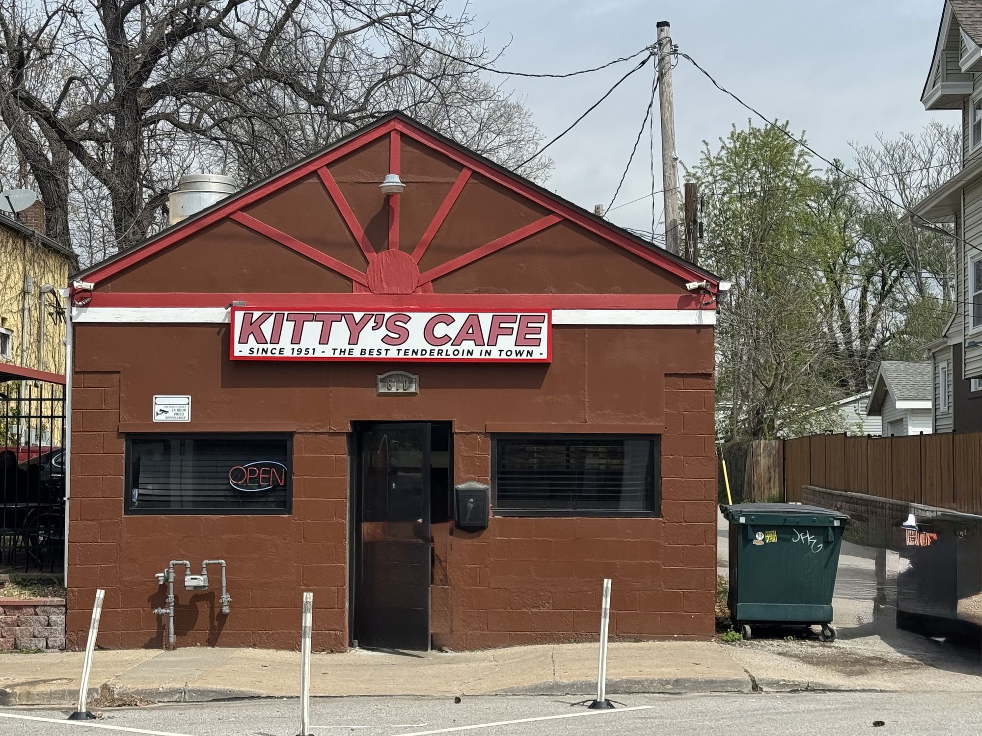 The Kitty's Cafe storefront on East 31st Street: a small building painted deep red, with a red sunburst gable and a hand painted sign reading Kitty's Cafe, since 1951, the best tenderloin in town